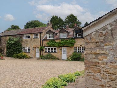 An outdoor view of a cottage with stone walls and gravel at The Old Bakery South Perrott near Mosterton