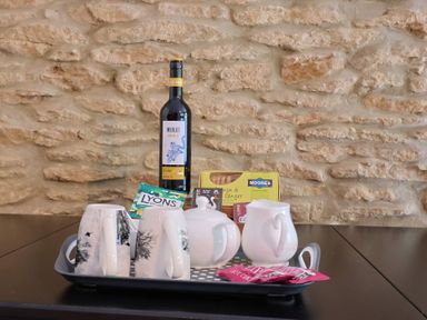 A tray with mugs, a wine bottle, milk jug, tea bags, and biscuits at Jasmine Cottage South Perrott near Mosterton