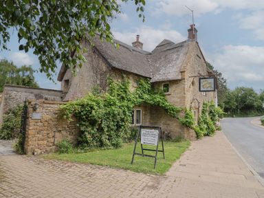 A cottage with a thatched roof and stone wall at The Old Barn at Jasmine Cottage South Perrott near Mosterton
