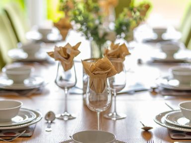 A dining table set with plates bowls spoons forks and wine glasses with napkins at Hazelseat House Graythwaite near Ulverston