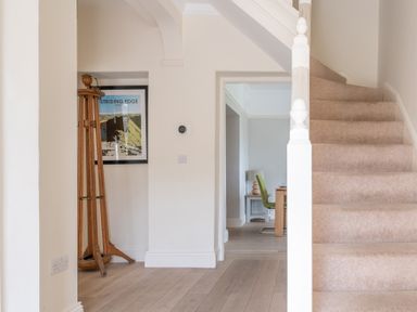 A beige carpeted staircase next to a hallway with wooden flooring and a framed picture on the wall at Hazelseat House Graythwaite near Ulverston