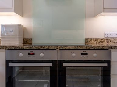 A kitchen counter with two built in neue ovens a bread box and granite countertop at Hazelseat House Graythwaite near Ulverston