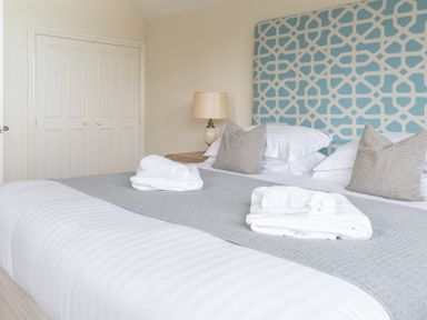 A bedroom with a bed with patterned headboard pillows and folded towels at Hazelseat House Graythwaite near Ulverston