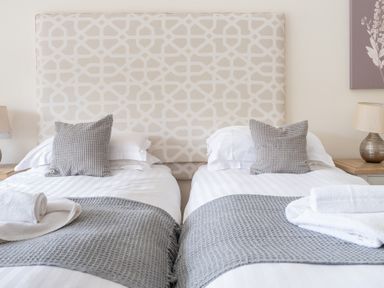 A bedroom with two single beds with patterned headboard and bedside tables with lamps at Hazelseat House Graythwaite near Ulverston