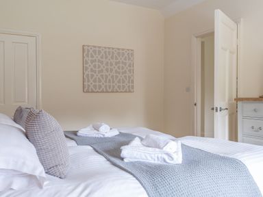A bedroom with two single beds side by side with grey pillows and towels on a grey runner at Hazelseat House in Graythwaite near Ulverston