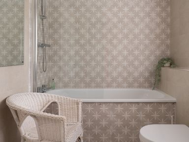 A bathroom with a bathtub and shower a wicker chair and a potted plant at Hazelseat House in Graythwaite near Ulverston