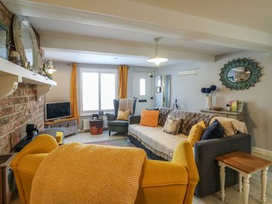 A living room with a yellow armchair sofa and television at Harbour Reach Brewers Quay Harbour
