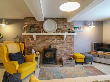 A living room with a yellow armchair a brick fireplace and a television at Harbour Reach Brewers Quay Harbour
