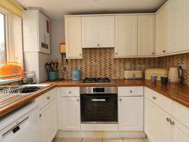 A kitchen with white cabinets wooden countertops and tiled backsplash at Harbour Reach in Brewers Quay Harbour