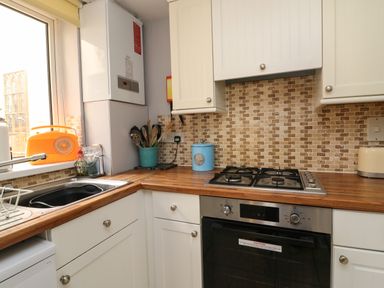 A kitchen with stove oven sink and utensils on countertop at Harbour Reach Brewers Quay Harbour