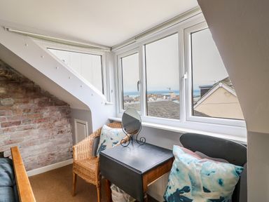 A small corner with two chairs a table and a decorative mirror by windows overlooking rooftops at Harbour Reach in Brewers Quay Harbour