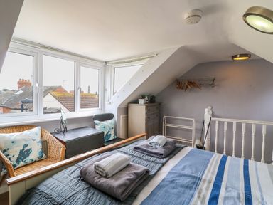 A bedroom with a bed towels chairs and windows overlooking rooftops at Harbour Reach Brewers Quay Harbour