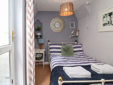 A bedroom with a double bed striped bedding and folded towels on it a bedside table with a lamp and wall decorations at Harbour Reach Brewers Quay Harbour