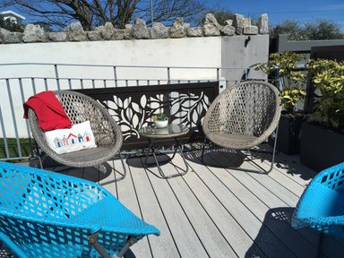 An outdoor patio with wicker chairs a small round table and plants at Steps Away in Benllech
