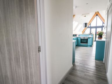 A narrow hallway leading to a kitchen with teal cabinets and appliances at Kerry Hill - The Sheepfold in Llanyre near Llandrindod Wells