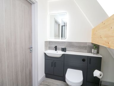 A bathroom with a toilet sink black cabinetry and a lighted mirror at Kerry Hill - The Sheepfold in Llanyre near Llandrindod Wells