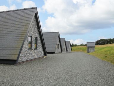 A row of stone buildings with pitched roofs along a gravel path in a grassy area at Kerry Hill - The Sheepfold in Llanyre near Llandrindod Wells