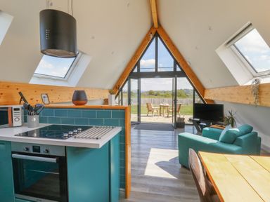 An open plan kitchen and living area with teal cabinets and a turquoise armchair at Kerry Hill The Sheepfold Llanyre near Llandrindod Wells