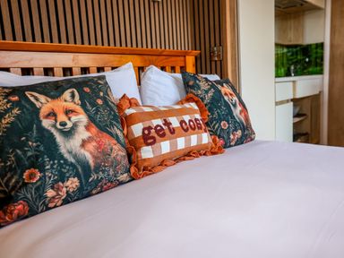 A bedroom with decorative pillows on a bed at The Fox Den Nantmel near Rhayader