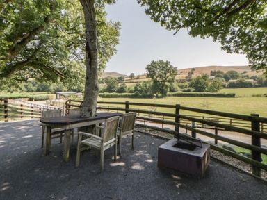 An outdoor area with a table and chairs near a fire pit at The Fox Den Nantmel near Rhayader