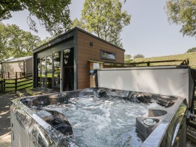 A hot tub next to a house with a view of trees at The Fox Den Nantmel near Rhayader