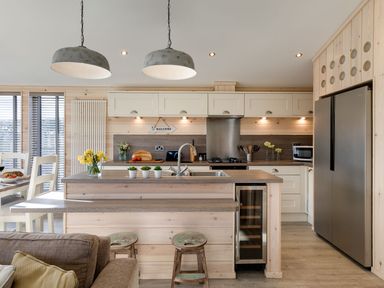 A kitchen with wooden cabinetry a center island stools and stainless steel appliances at Lobster Lodge in Runswick Bay