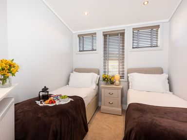 A bedroom with two single beds a bedside table with a lamp and flowers and a breakfast tray at Lobster Lodge in Runswick Bay