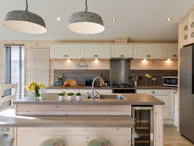 A kitchen with a countertop island and sink with flowers on the counter at Lobster Lodge in Runswick Bay