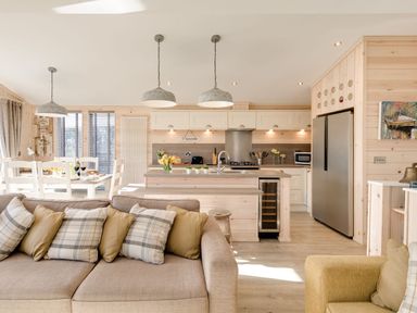 An open plan kitchen and dining area with a sofa and armchair in a wooden interior at Lobster Lodge Runswick Bay