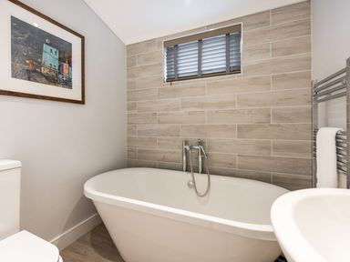 A bathroom with a freestanding bathtub wooden tiled wall and a framed picture at Lobster Lodge in Runswick Bay