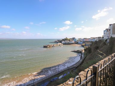 A coastal view with a harbor promenade and buildings on a hillside at Cwtch Lodge 42 in Stepaside near Wisemans Bridge