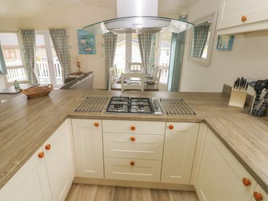 A kitchen with stove and wooden countertops looking into a dining area with table and chairs at Cwtch Lodge 42 Stepaside near Wisemans Bridge