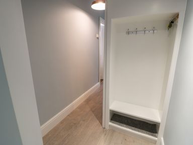 A hallway with a built-in shelf and hooks for hanging items at Bryn Derfel in Borth-y-Gest near Porthmadog