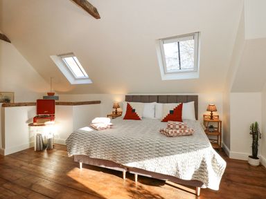 A bedroom with a double bed under two skylight windows and wooden floors at The Little Hay Barn in Bacton
