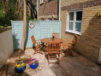 An outdoor patio with a wooden table and chairs and potted flowers at Castle Cove View in Castle Cove