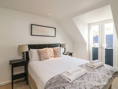 A bedroom with a double bed pillows bedside tables and lamps near a window at Castle Cove View in Castle Cove