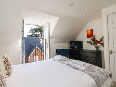 A bedroom with a bed towels and a blanket a black dresser a TV a chair and an open window with a view at Castle Cove View in Castle Cove
