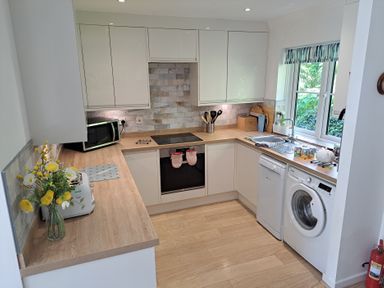 A kitchen with a stove, microwave, sink, and washing machine at Castle Cove View, Castle Cove