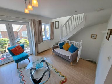 A living room with a sofa and armchair near a staircase at Castle Cove View in Castle Cove