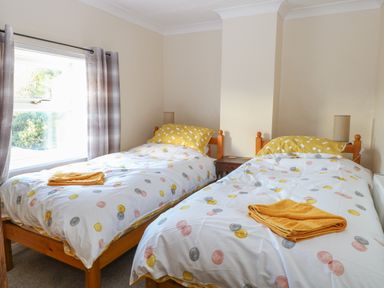 A bedroom with two single beds with polka dot bedding and yellow towels at Rose Cottage in Downham Market