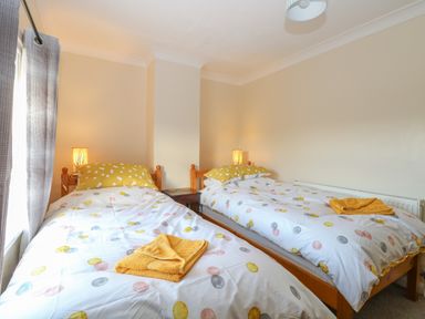 A bedroom with two single beds with polka dot bedding and yellow towels at Rose Cottage in Downham Market