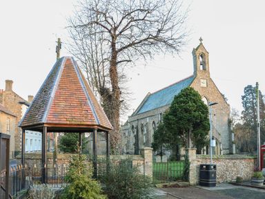 A church and a wooden gazebo with a tiled roof in a fenced garden area at Rose Cottage in Downham Market