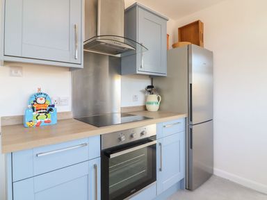 A kitchen with light blue cabinets stainless steel oven and refrigerator at Pepperpots in Mawgan Porth