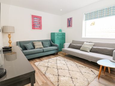 A sitting room with two sofas a patterned rug a lamp and framed pictures at Pepperpots in Mawgan Porth
