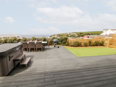 An outdoor patio with a hot tub dining table chairs and a barbecue grill at Pepperpots in Mawgan Porth