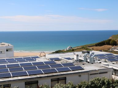 Rooftop solar panels on buildings with a beach and ocean in the background at Pepperpots in Mawgan Porth