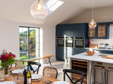A kitchen and dining area with a wooden table set with plates and glasses and a vase of flowers Bennar Fawr Dyffryn Ardudwy