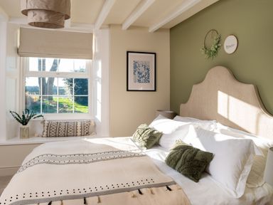 A bedroom with a bed pillows window and wall decorations at Bennar Fawr in Dyffryn Ardudwy