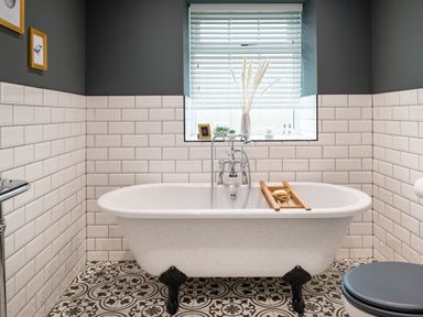 A bathroom with a clawfoot bathtub a window with blinds and decorative tiles on the floor at Bennar Fawr in Dyffryn Ardudwy