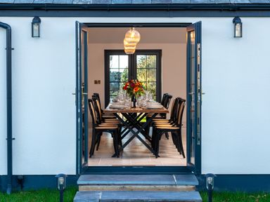 A dining room with a long table and chairs set for a meal with flowers in the center at Bennar Fawr in Dyffryn Ardudwy